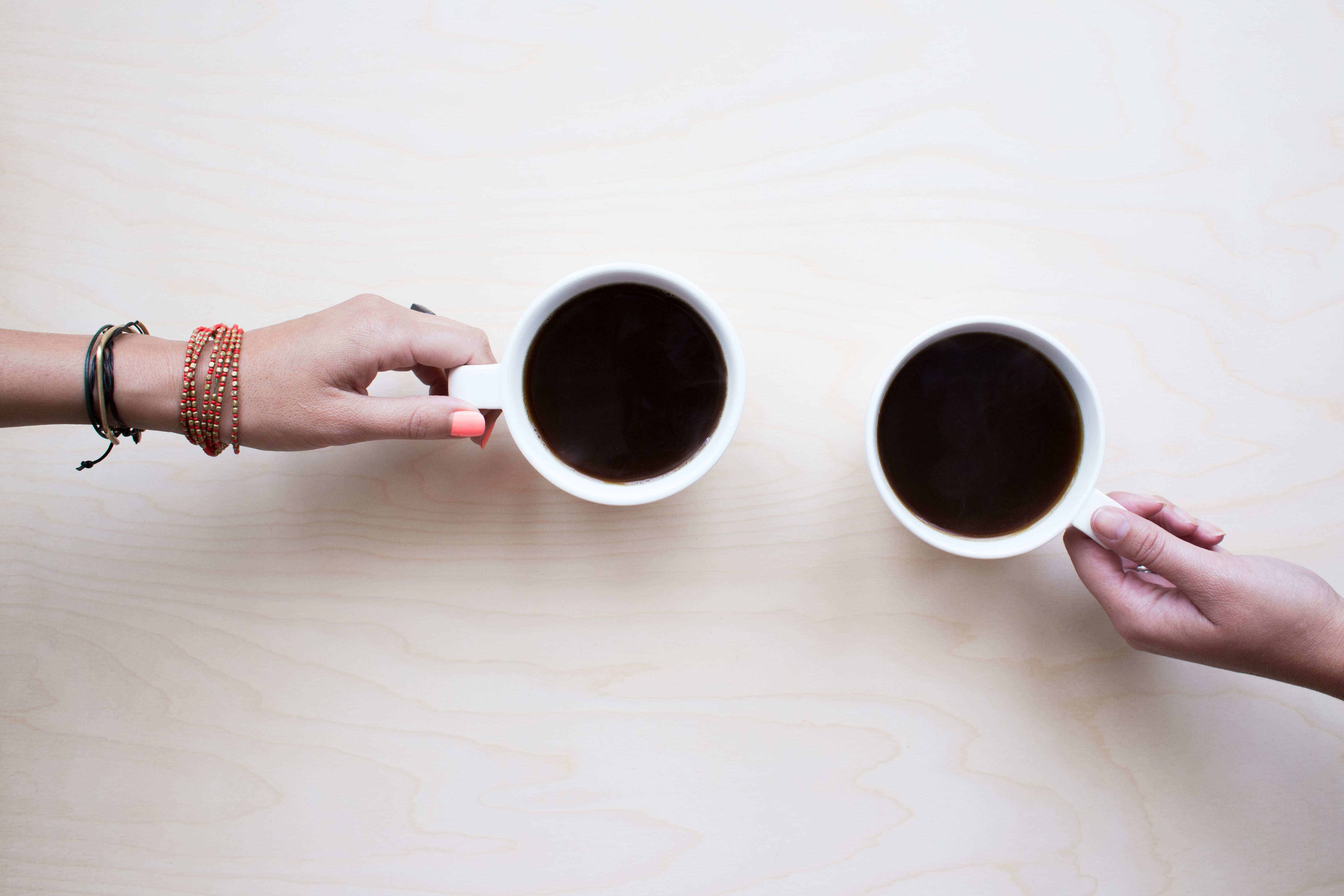 two hands holding onto a coffee cup each